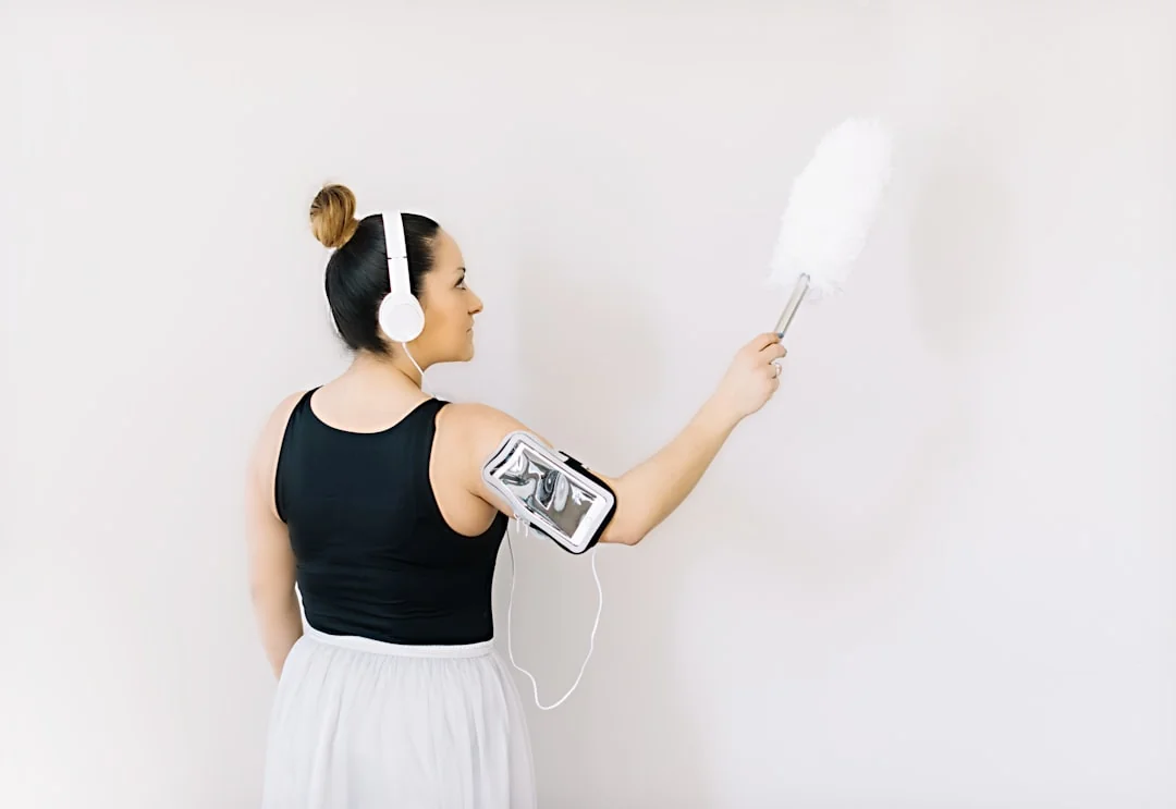 Un homme nettoyant une porte vitrée à l'intérieur avec un vaporisateur et un chiffon.